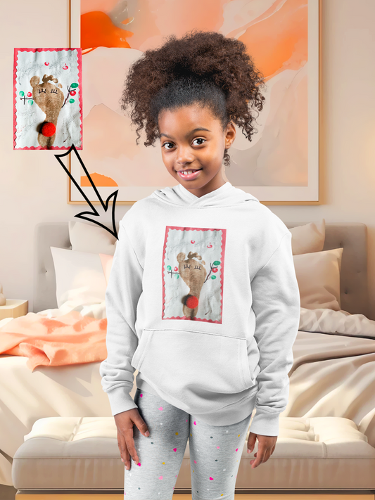 A toddler wearing a white hoodie with a unique toddler foot print artwork design, standing in a cozy room setting.